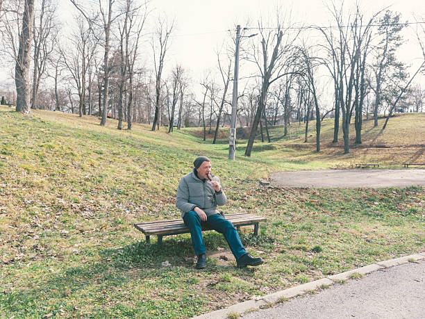 Man eats ice cream on stick on cold winter day outdoors in public park