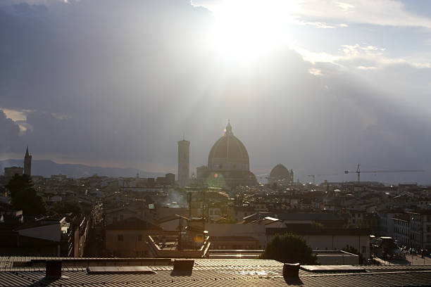 Cityscape of Florence, Italy, featuring the Cathedral of Santa Maria del Fiore illuminated by strong sunlight. Historic Italian architecture under a dramatic sky, ideal for travel, tourism, and European city concepts.