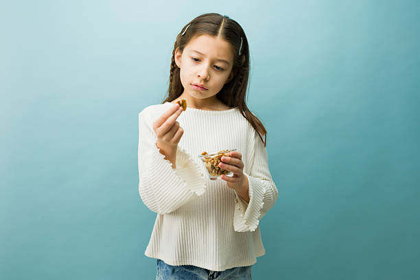 Little girl showing concern while holding a walnut, representing childhood nut allergies and dietary restrictions