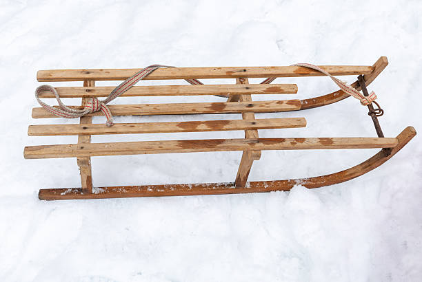 A sled stands on a snowy country road on a gray, cloudy winter day; no person on the sled.