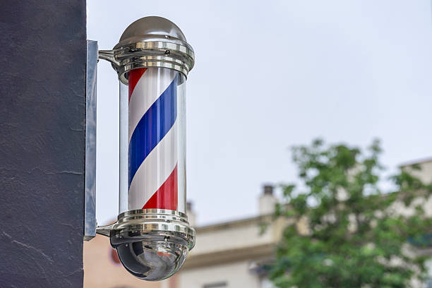 Close-up of a traditional barber pole spinning on a barbershop facade with copy space.