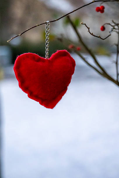 Stock photo showing elevated view of mottled red-black background with  3D felt red and white love heart bunting border, Valentine's Day greeting card sign.