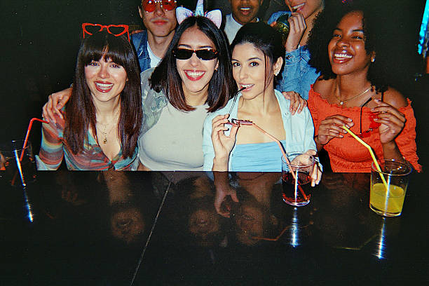 Group of diverse young adult friends smiling and enjoying drinks at a vibrant party, capturing a moment of friendship and youthful celebration with a nostalgic film aesthetic