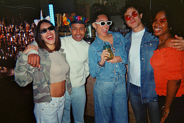 Diverse group of young adults smiling and posing together at a vibrant retro-themed party, candid celebration of friendship, joy, and carefree weekend nightlife energy