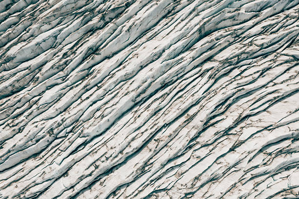 Glacier surface in Iceland displaying a rugged texture with deep crevasses and cracks, revealing geological formations and the impact of climate change on the environment