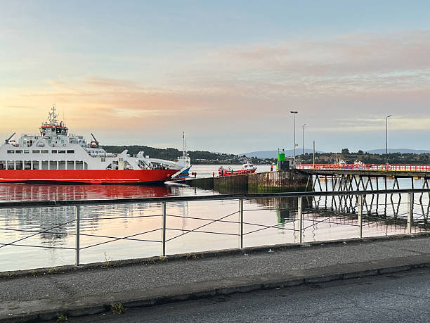 A ferry waits at the pier in the early morning light while crew members prepare for boarding vehicles and cargo, departing from Chiloé Island in southern Chile.Daily transport routines that connect island communities with the mainland. Regional maritime transportation and everyday travel in Chile’s island regions.