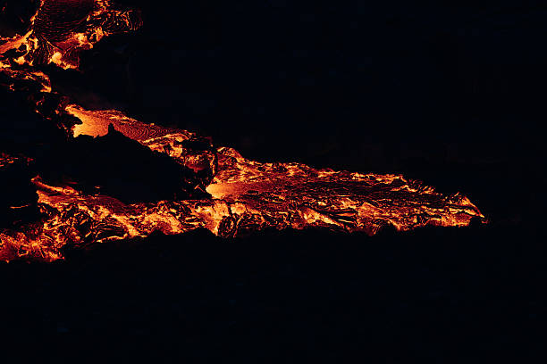 Molten lava streams flowing over dark volcanic rock at night during an eruption in Iceland, highlighting the immense heat and dynamic geological activity of the earth