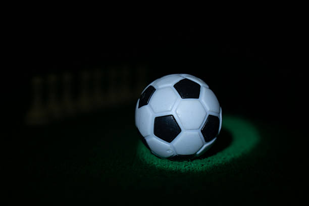 A yellow soccer ball with green accents lies on a white background.