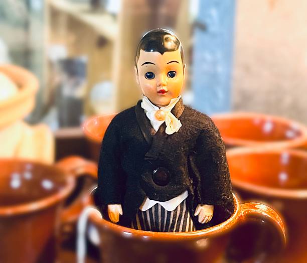 Antique groom doll in teacup, color photo.