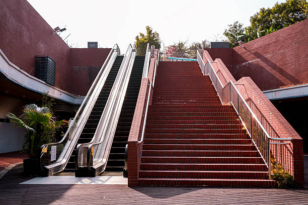 Modern Urban Staircase: Red Brick Steps and Escalators Leading Upward in a Public Space