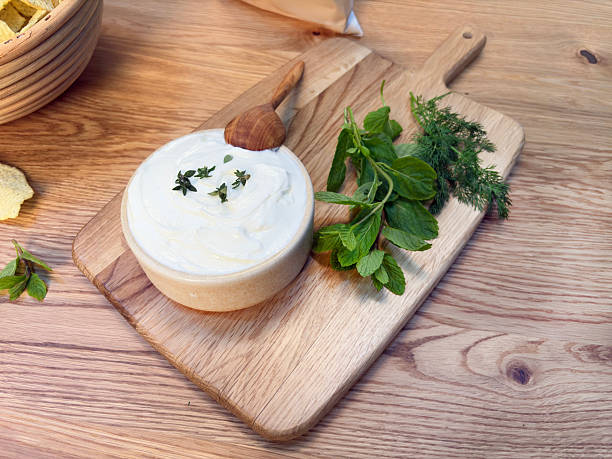 Detail of female hands holding slice of homemade whole meal bread with homemade kefir cheese spread and fresh spring onions - healthy nutrition concept