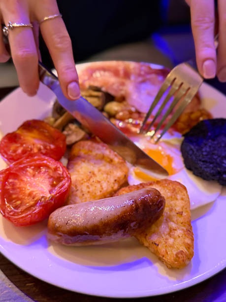 Image of hearty full English fried breakfast with sausage, egg, baked beans, hashbrown, tomato, mushrooms, traditional British morning meal