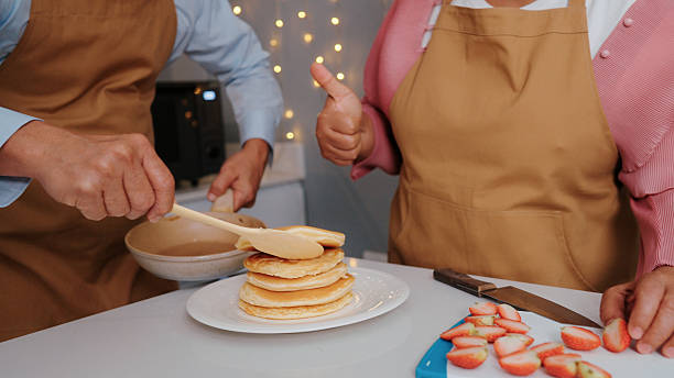 Senior couple preparing pancakes in the kitchen.