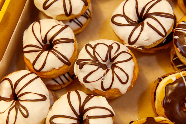 A box of donuts with chocolate and white frosting. There are many different types of donuts in the box