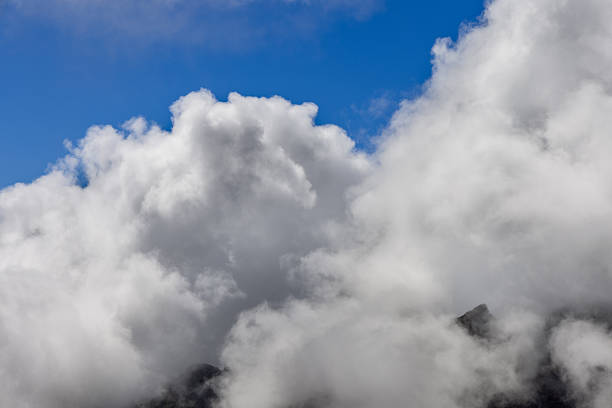 Towering cloud forms over hidden peaks in blue sky, minimal vapor and light for abstract backdrop in branding layouts posters