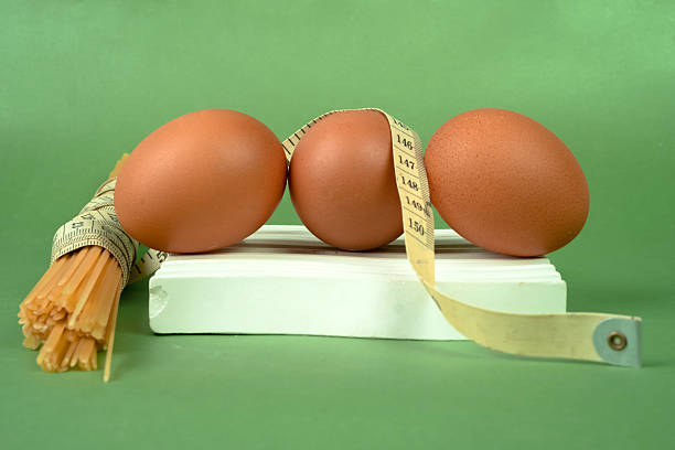 Chicken egg and measuring tape on a white coaster on a green background. Diet and healthy living concept