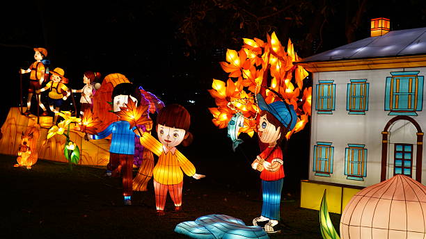 A beautiful night scene captures a festive outdoor lantern display, featuring cheerful child figures, a squirrel, a fish, and glowing leaves around an illuminated house. This charming artwork evokes themes of childhood wonder, celebration, and traditional light festivals worldwide.