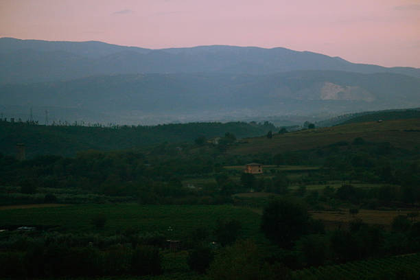 Sunset landscape with the sun disappearing behind hills and mountains under a dramatic sky. Warm evening light creates a calm and atmospheric scene inspired by nature, travel and reflection.