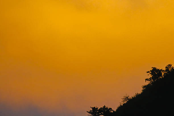 Sunset landscape with the sun disappearing behind hills and mountains under a dramatic sky. Warm evening light creates a calm and atmospheric scene inspired by nature, travel and reflection.