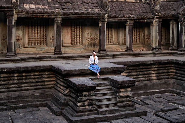 Woman sitting alone on a stone platform inside the Angkor Wat complex