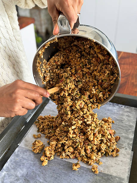 Image of hand mixing crunchy granola with oats pumpkin seeds almonds nuts and dried fruit fresh homemade breakfast cereal preparation