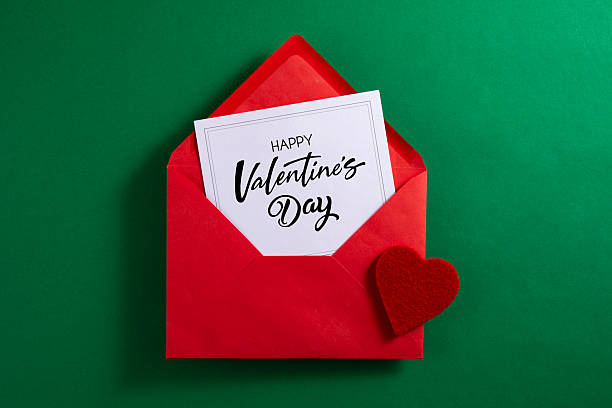 Red envelope and greeting card for Valentine’s Day on green background