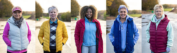 A collage of a diverse group of five older women standing outdoors on a paved path near water, dressed in casual fall clothing. Each woman wears a warm jacket or vest and has her hands in her pockets, smiling confidently at the camera. The background features soft-focus autumn trees and a natural park setting, conveying an active, healthy lifestyle, friendship, and independence in later life.Images are available similar to this scenario.