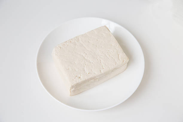 A piece of tofu on a white plate on a white background