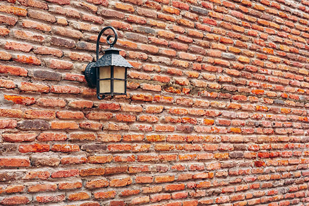 A light fixture hangs on a brick wall in an outdoor area during daytime hours.