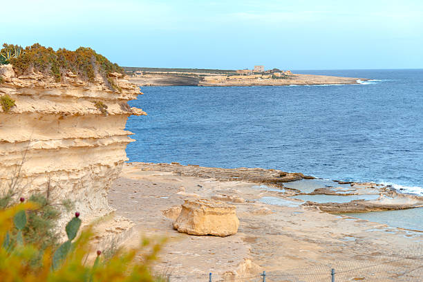 Stunning coastal landscape featuring the layered sandstone cliffs of Delimara, Malta. Ideal for travel brochures, Mediterranean tourism campaigns, and website banners.