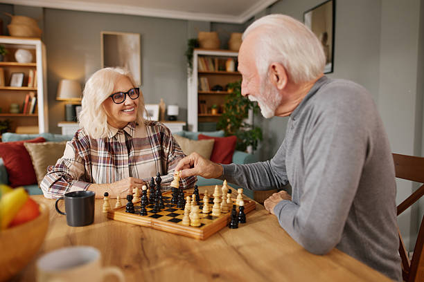Senior couple playing chess at home, enjoying leisure time