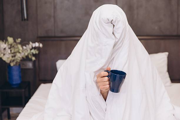 istock Sleepy Man Hiding Under Blanket Holding Coffee Cup in Bed 2259863176