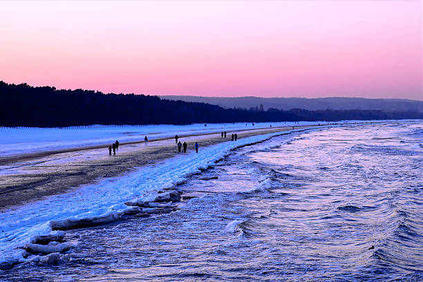Winter baltic Beach with snow Icy Waves and sunset sky over