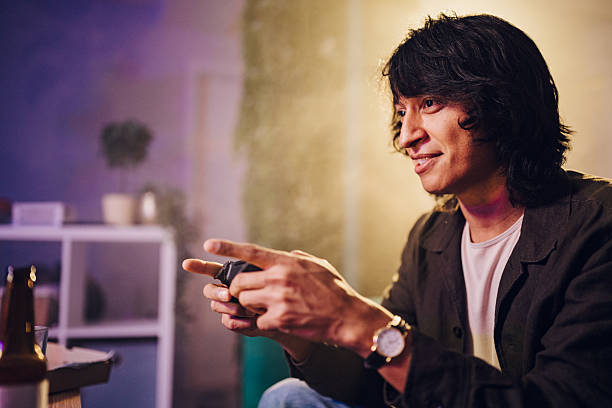 Man holding a video game controller, concentrating and smiling while enjoying leisure gaming time indoors