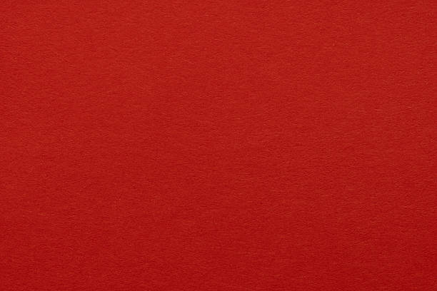 High-resolution close-up of a vibrant red paper texture with a subtle grainy surface, ideal for holiday backgrounds, Christmas cards, or creative design projects.
