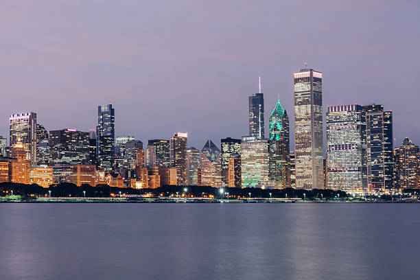 As daylight fades, city lights begin to glow across the Chicago skyline, reflecting the transition from day to night.
