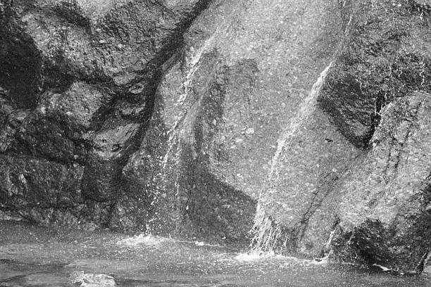 Black and white close-up of a small waterfall flowing over textured rock near Big Four Mountain, Washington, highlighting natural erosion and contrast.