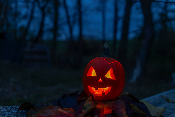 Carved pumpkin with spooky face illuminating the night scenery