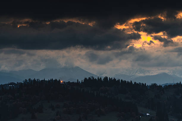 istock Stormy sky above forested hills and mountain range at dusk, heavy clouds illuminated by warm light, atmospheric countryside landscape with dramatic contrast and depth 2259880134