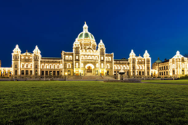 The majestic architecture of the British Columbia Parliament Buildings under a clear blue sky in Victoria, Canada.