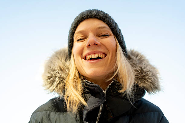 Young adult woman enjoying cold weather, smiling and laughing with eyes closed