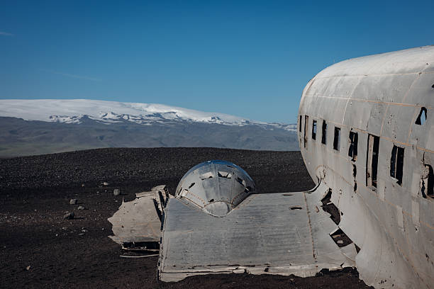 Solheimasandur plane wreck showing the abandoned Douglas DC-3 fuselage on black volcanic sand with mountains and a glacier in the distance under a clear blue sky
