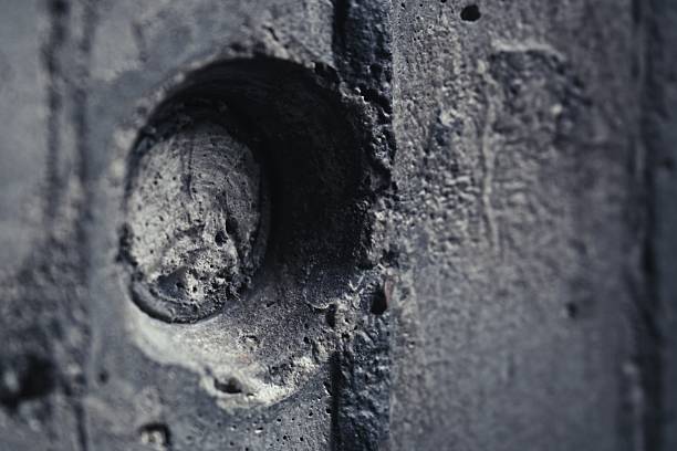 Artistic side view of a round tie hole in architectural concrete wall. Selective focus on edge with vertical formwork lines. Minimalist industrial background with soft blur for premium design mockup.