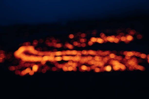 Glowing orange lava creating an abstract bokeh effect, representing the intense heat and movement of a volcanic eruption flowing across rugged terrain at night in Iceland