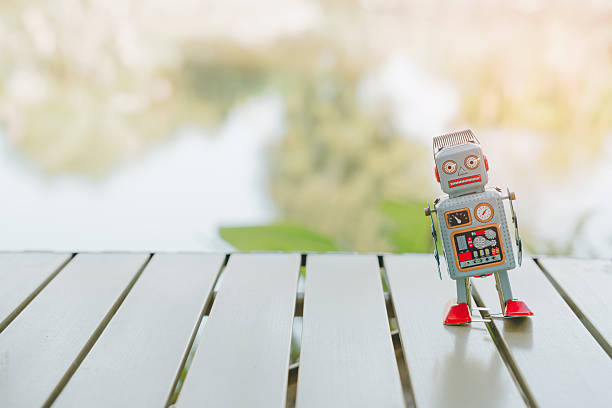 Ai concept. Retro robot toy standing on wooden table with blurred natural background, evoking nostalgic and playful feeling.