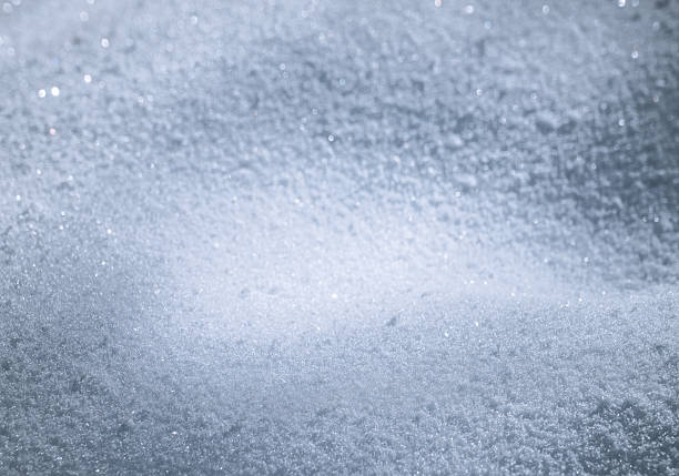 Close-up of sparkling, frosted snow with soft blue tones creating a serene winter mood. Ideal for themes of cold, calm, frost, and seasonal atmosphere in photography and design.