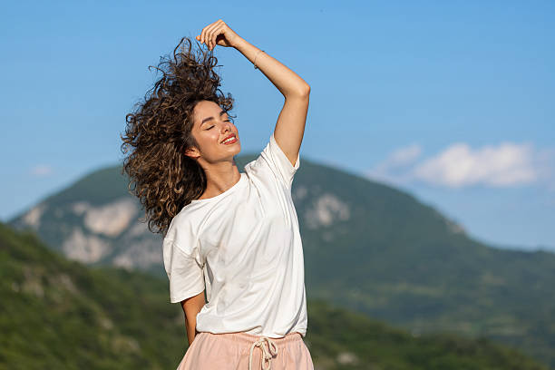 A curly-haired beauty in a simple attire takes in the beauty of the great outdoors.