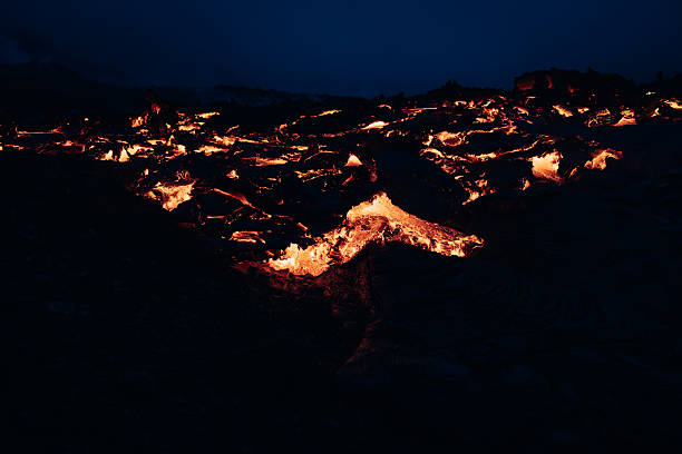 Bright orange molten lava creating a fiery river and a dramatic natural light show, highlighting the raw power and beauty of a volcanic eruption in Iceland