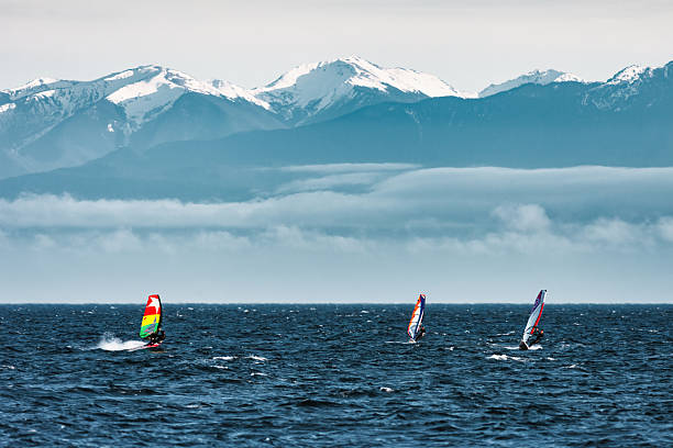 Windsurfers surf in the Strait of Juan de Fuca near Victoria, British Columbia, Canada, on an overcast day.