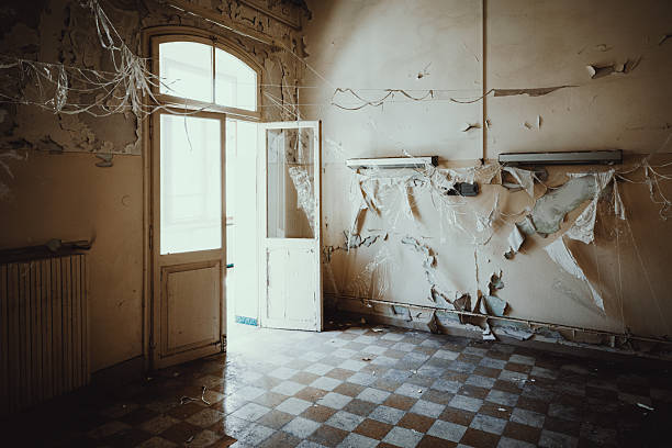ruined walls of a historic site from the 20th century with windows and a collapsing floor in the countryside in Poland.